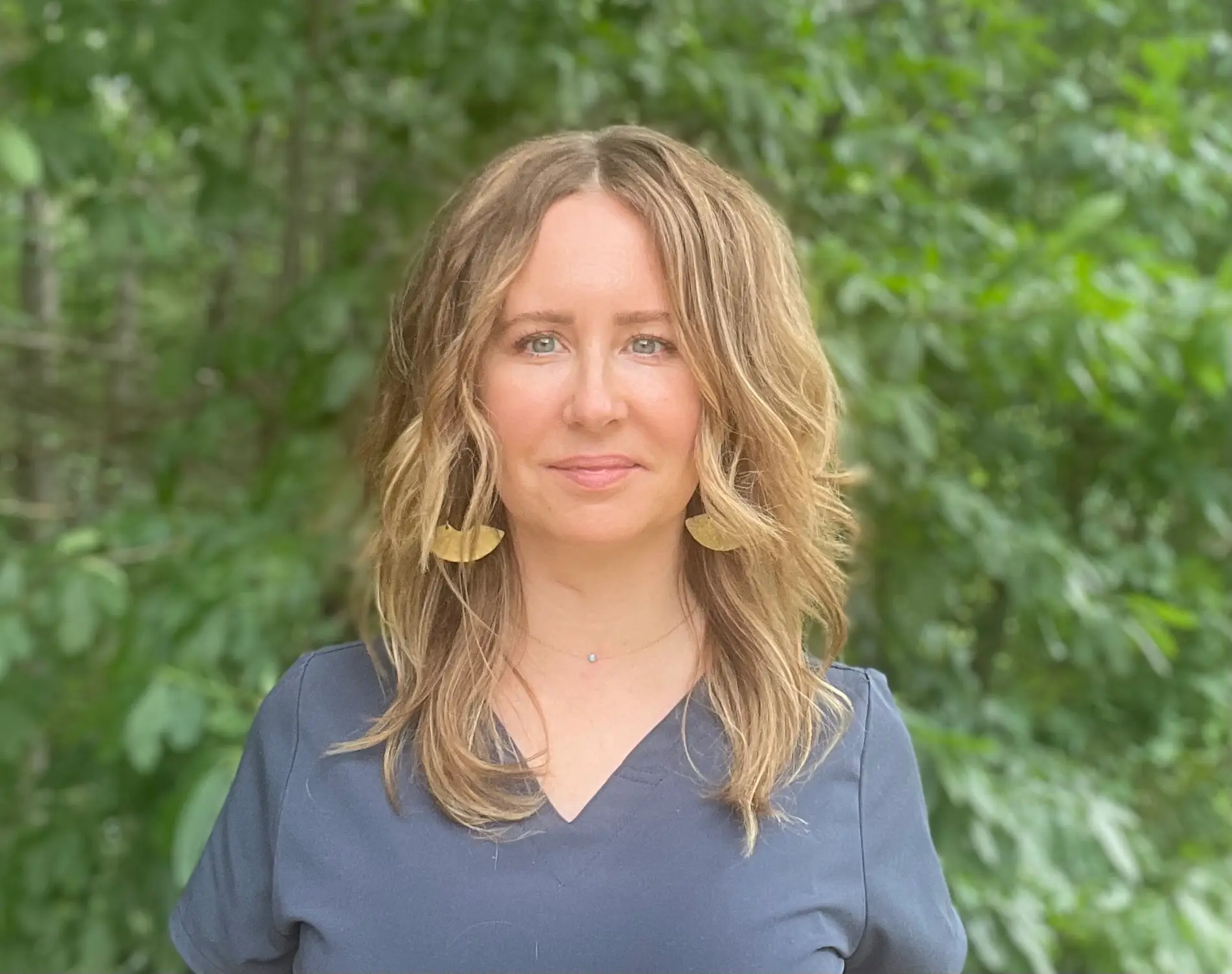 Julie Wawro, owner and licensed esthetician, in front of soft greenery