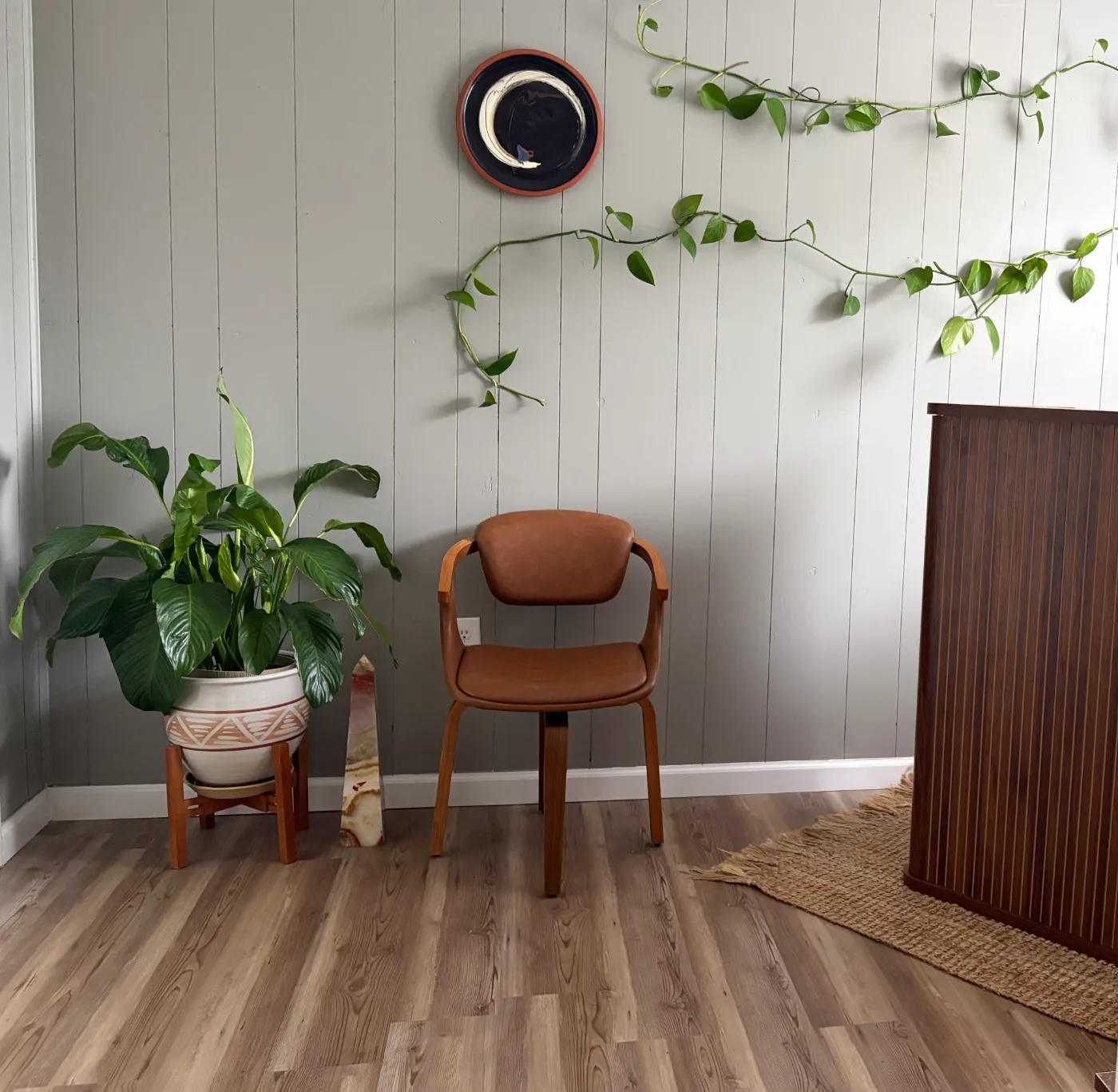 A leather chair in a calm corner of the studio, plants trailing along the wall